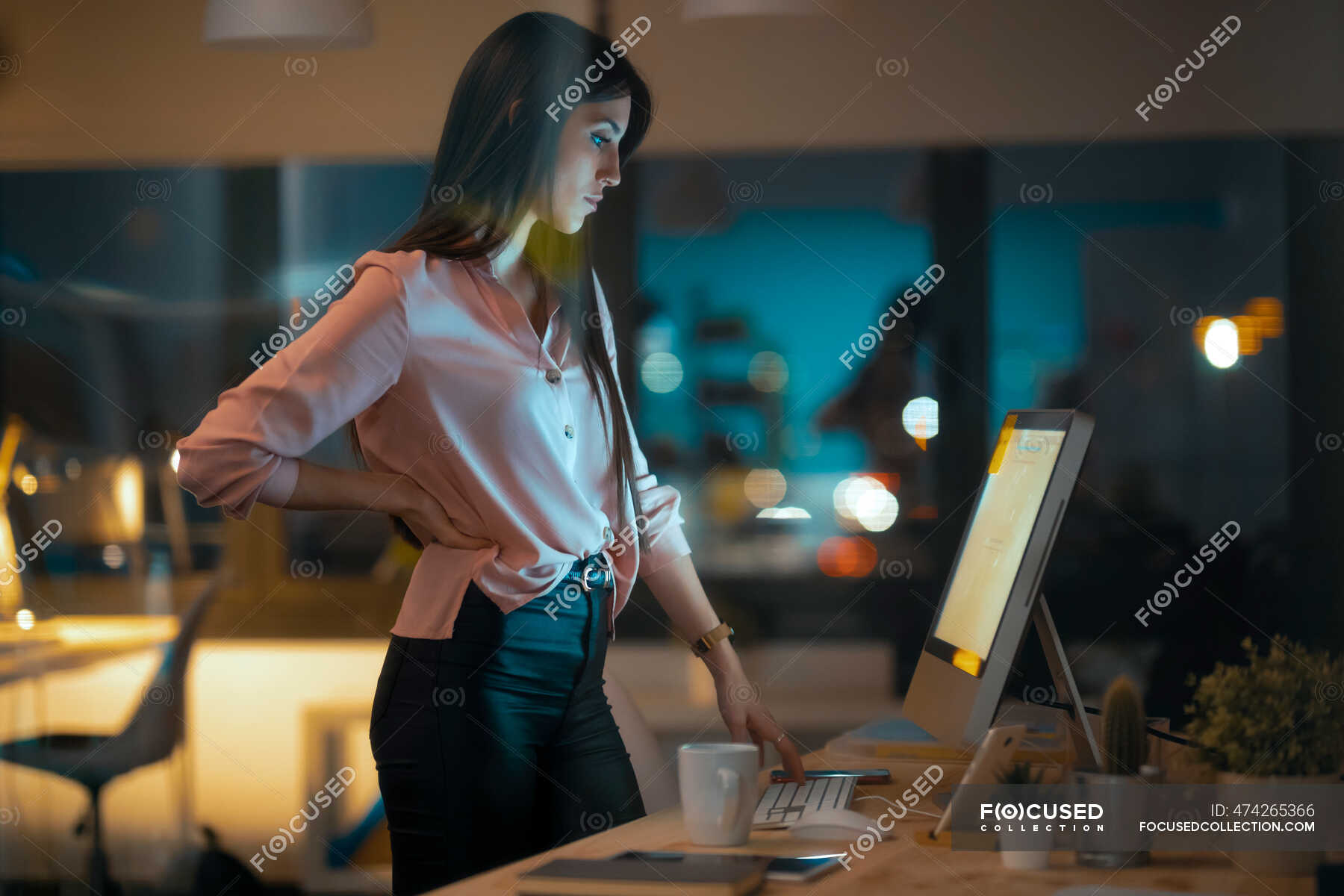 Serious young woman standing at desk in office looking at computer —  technology, businesswoman - Stock Photo | #474265366
