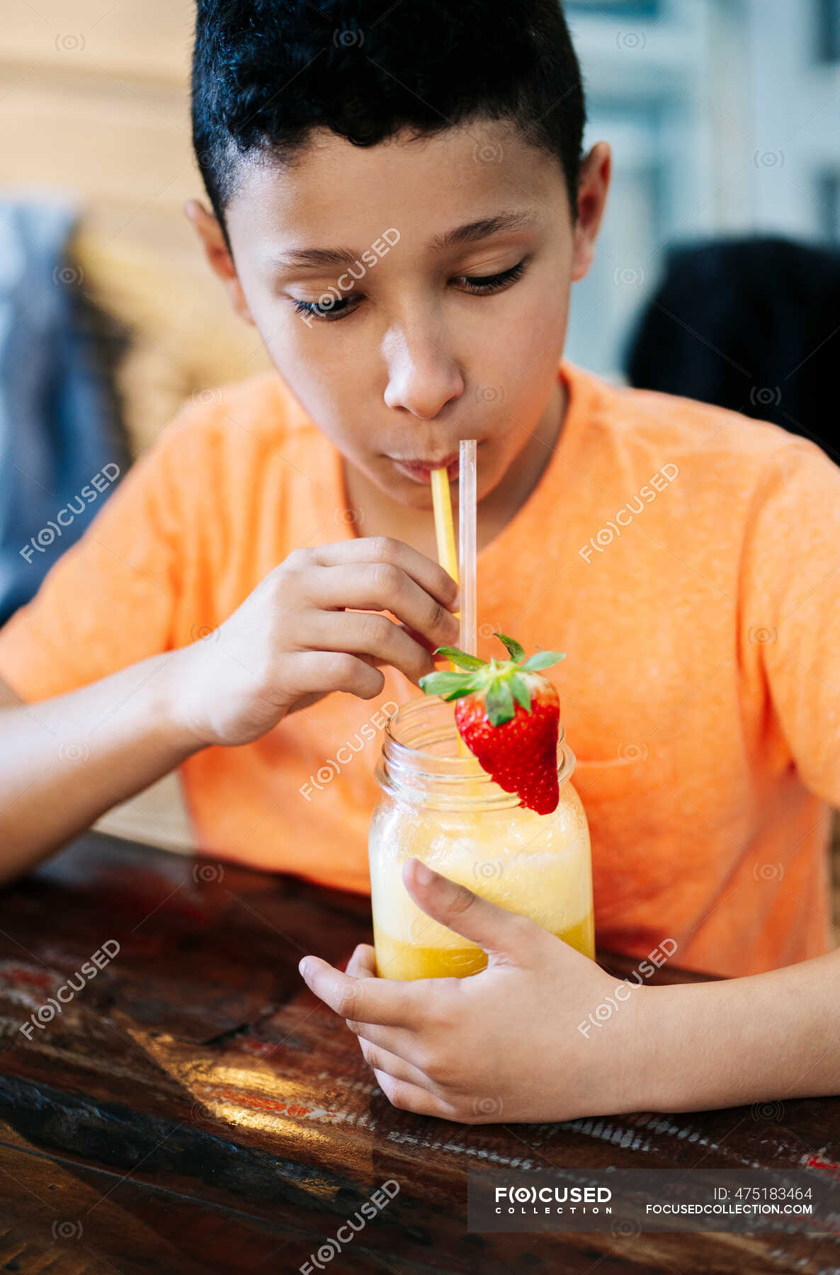 Boy drinking smoothie from straw while sitting at table in restaurant —  Food and drink, Elementary Age - Stock Photo | #475183464