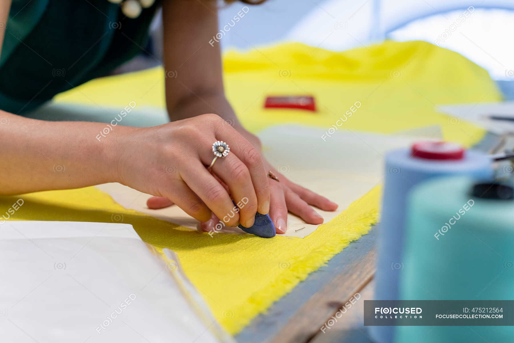 female-fashion-designer-marking-on-yellow-fabric-at-studio-textile