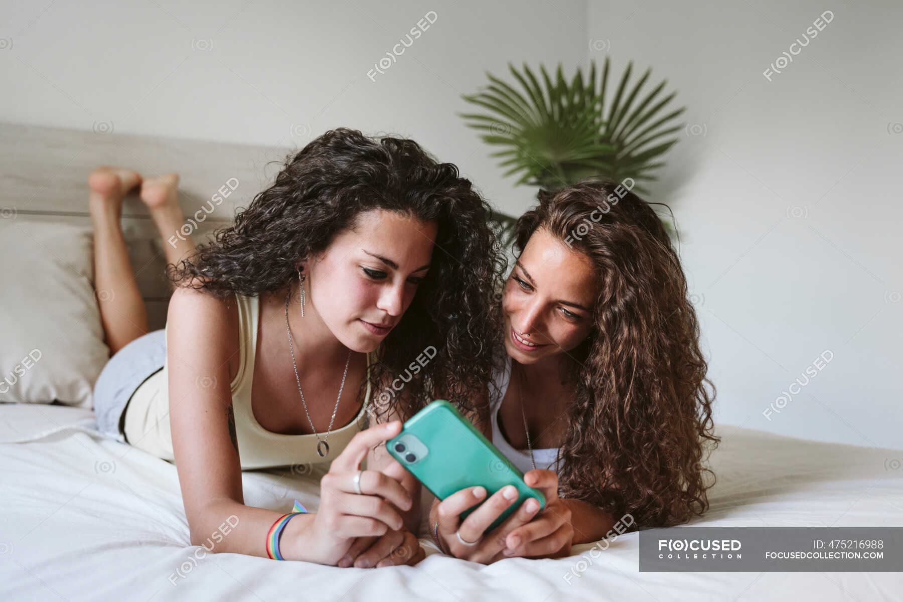 Lesbian couple using smart phone while lying on bed at home — leisure ...