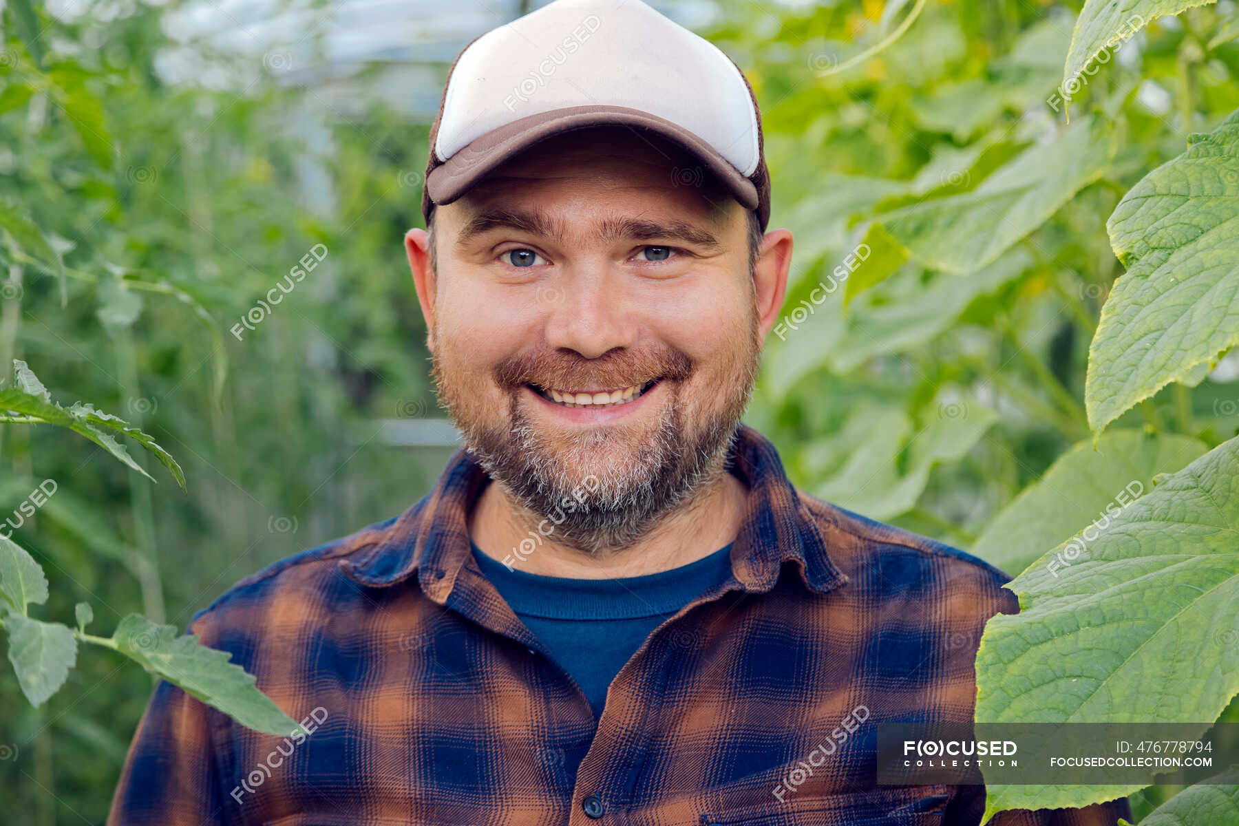 portrait-of-smiling-farmer-in-a-greenhouse-garden-mid-adult-men