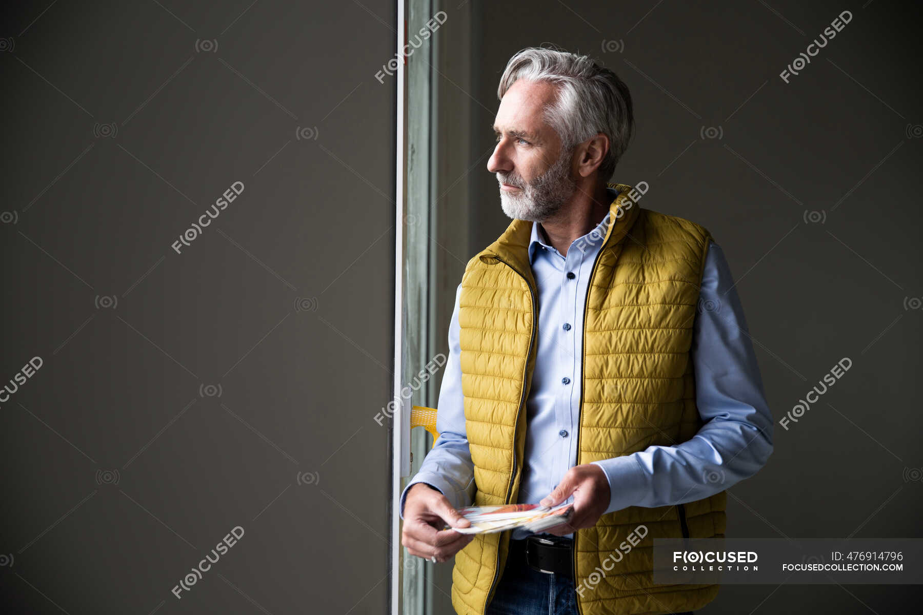 Thoughtful male architect wearing jacket looking through window in