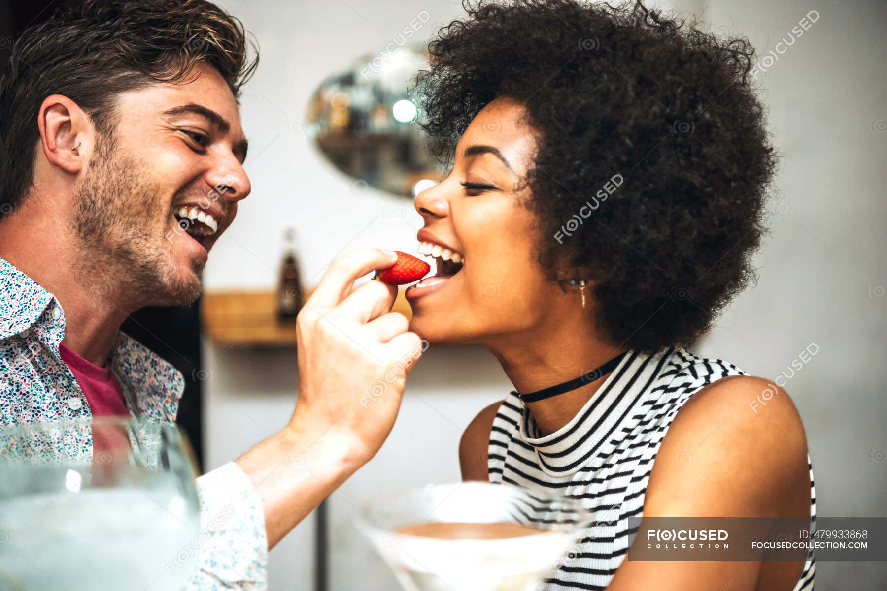 Close Up Of Cheerful Man Feeding Strawberry To Girlfriend In Restaurant — Headshot Togetherness