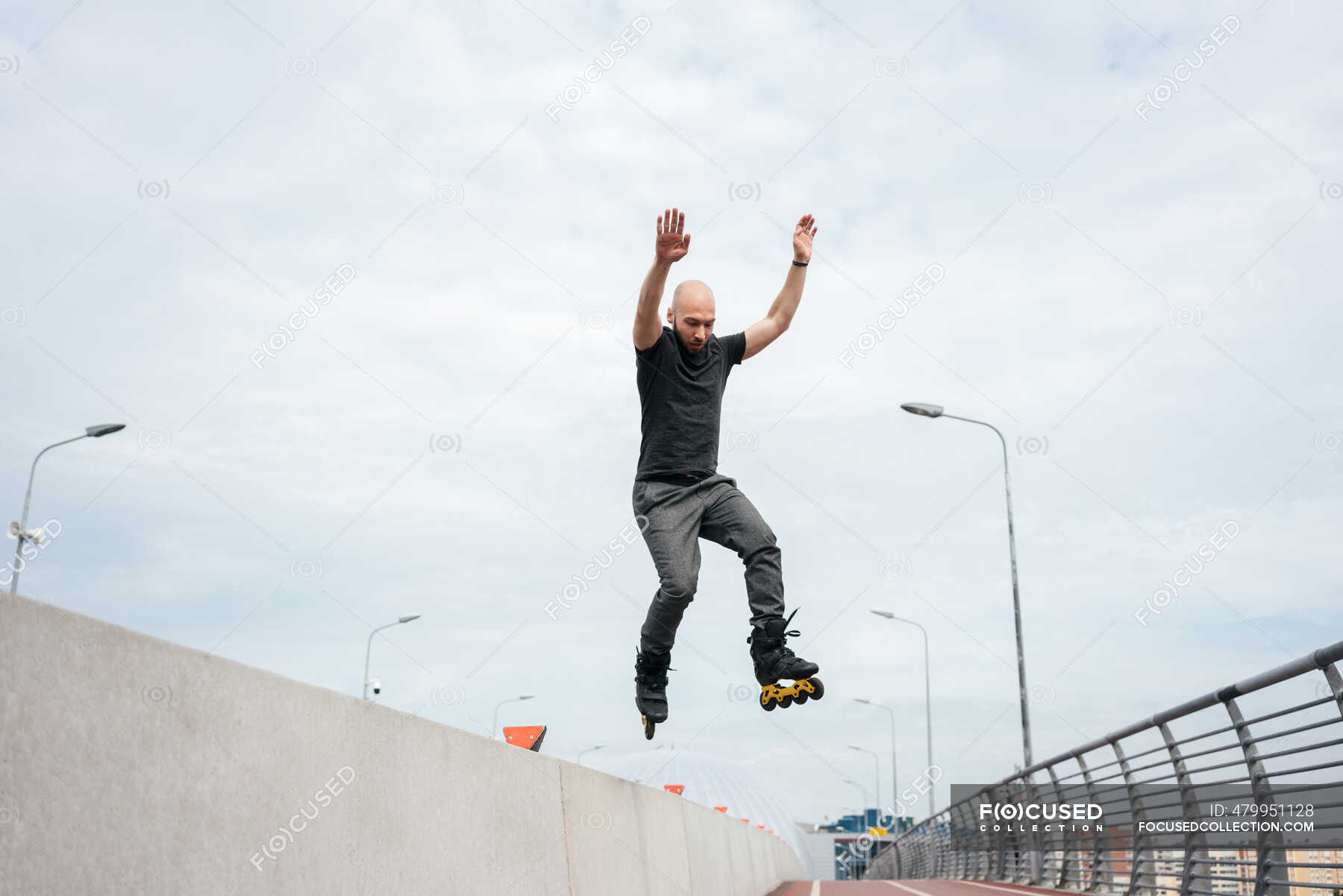 Young man with inline skates jumping on bridge against sky — skating