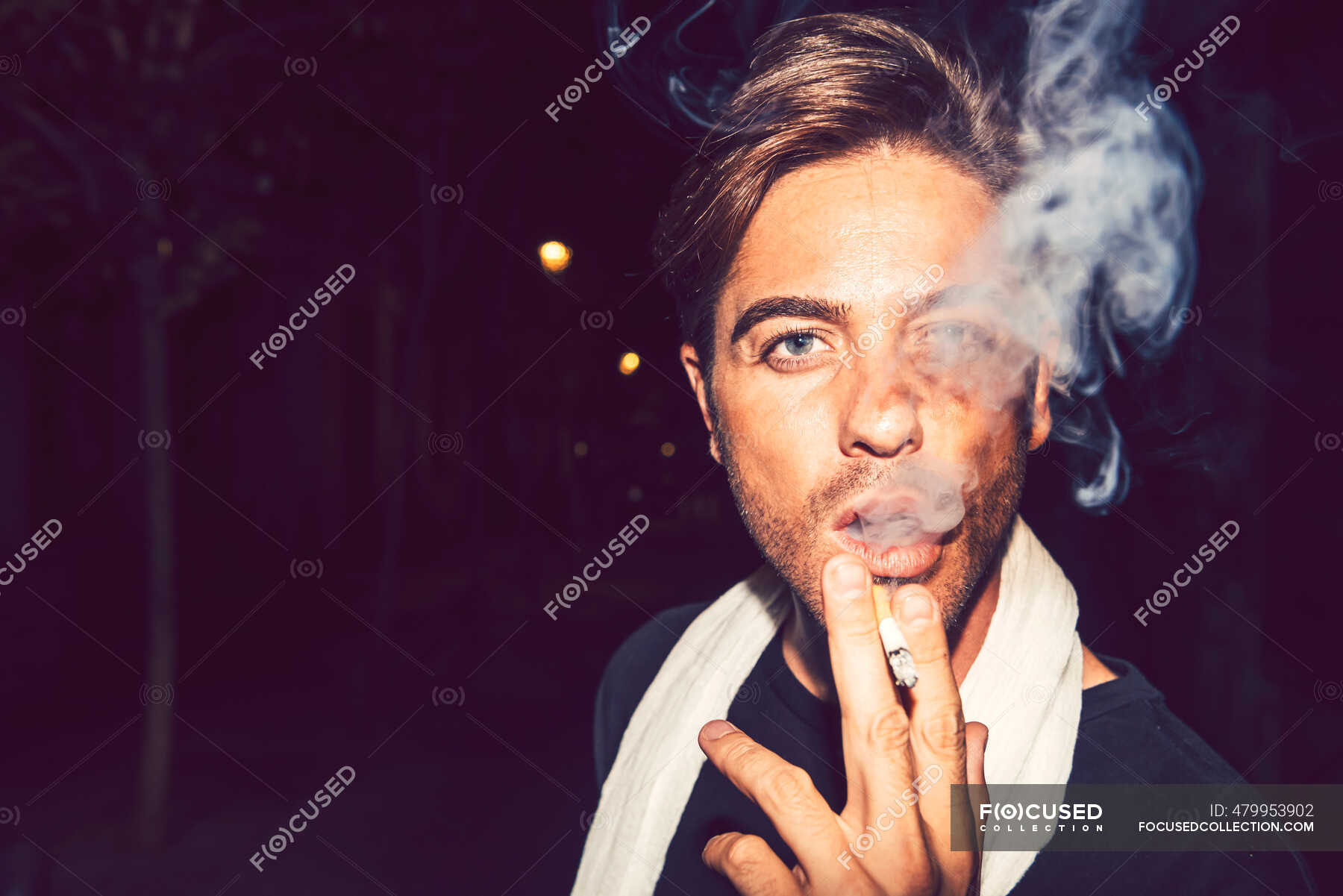 Close-up of handsome man smoking cigarette outdoors at night — head ...