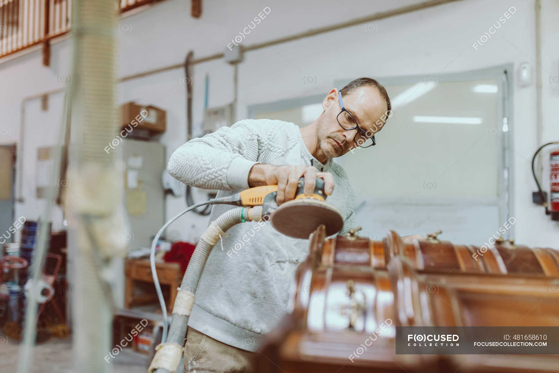 Male expertise polishing furniture with sander while standing at