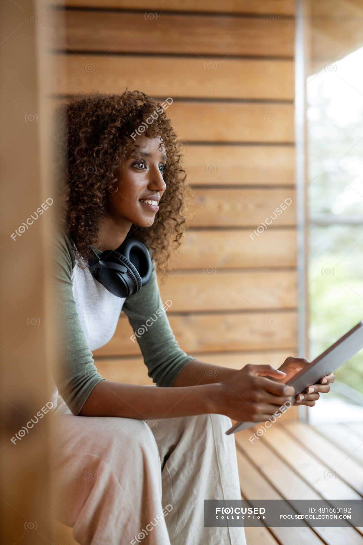 Young woman with headphone using digital tablet while sitting at home ...