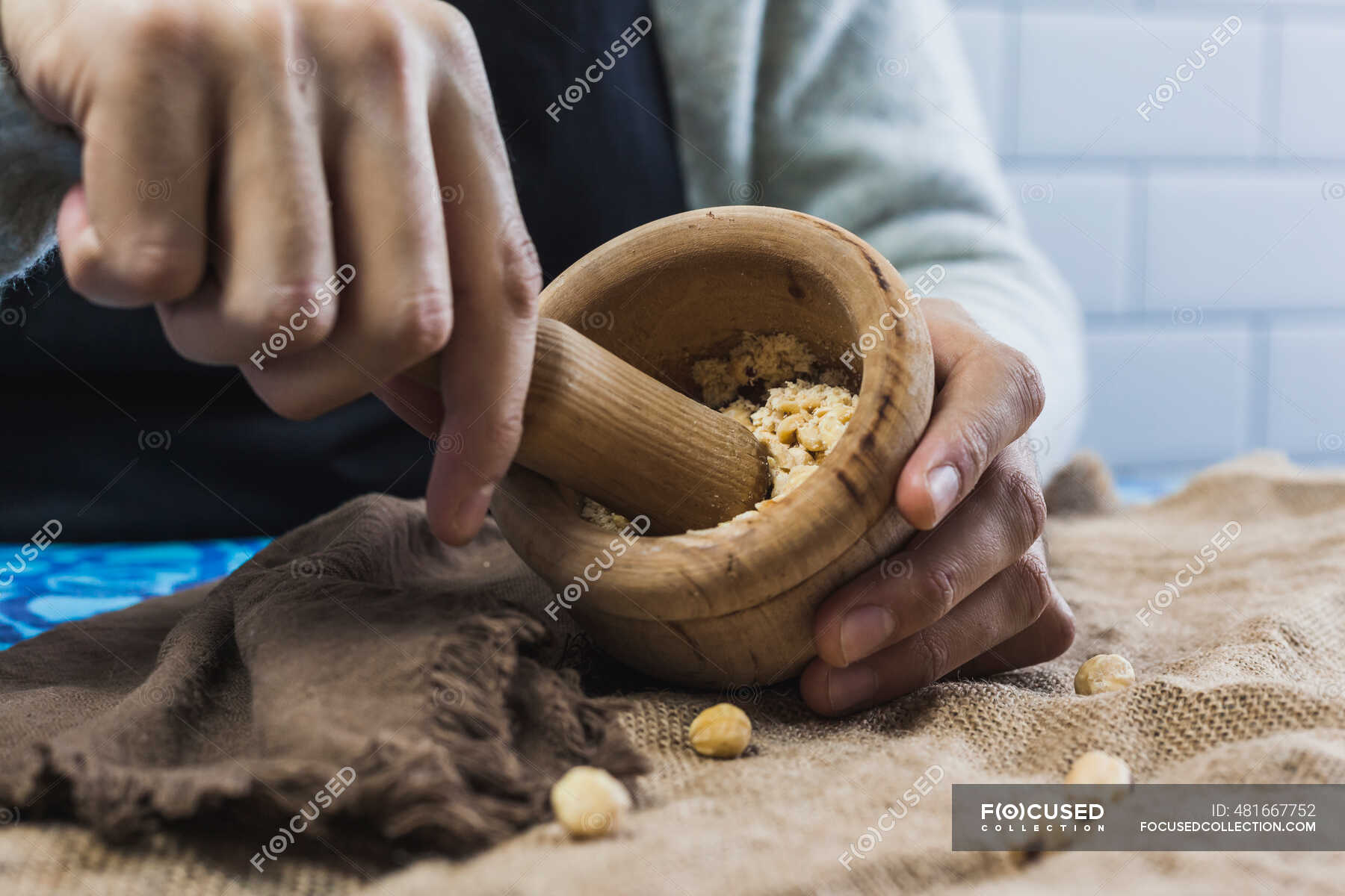 Hands of man grinding hazelnuts with mortar and pestle — food, one