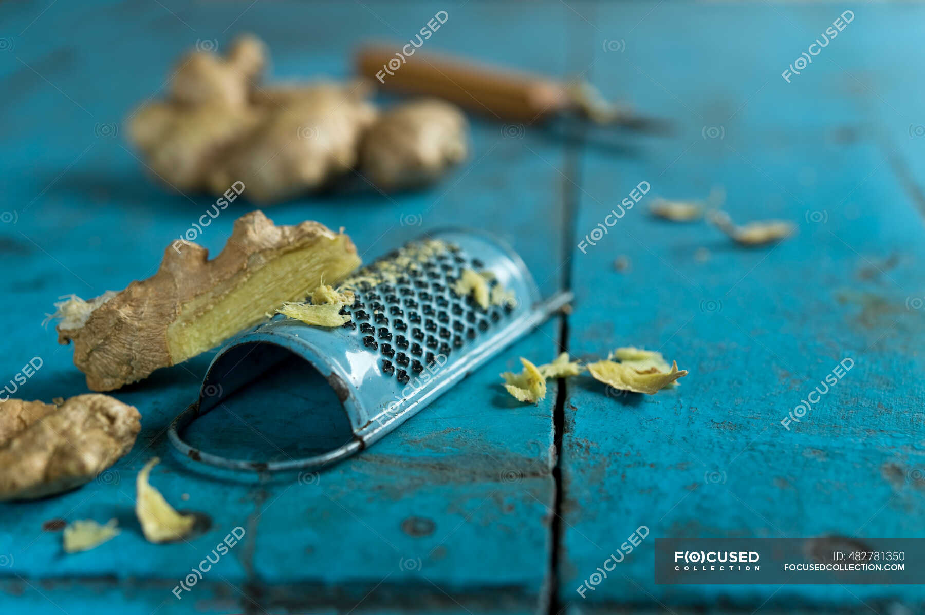 Ginger root and grater lying on blue wooden surface — plant, peeling