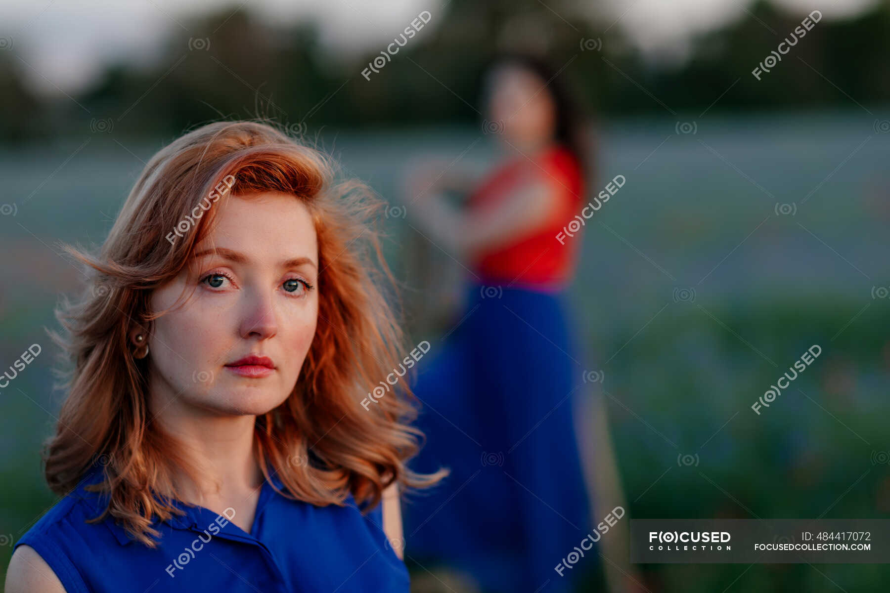 confident-woman-on-field-while-female-friend-in-background-portrait