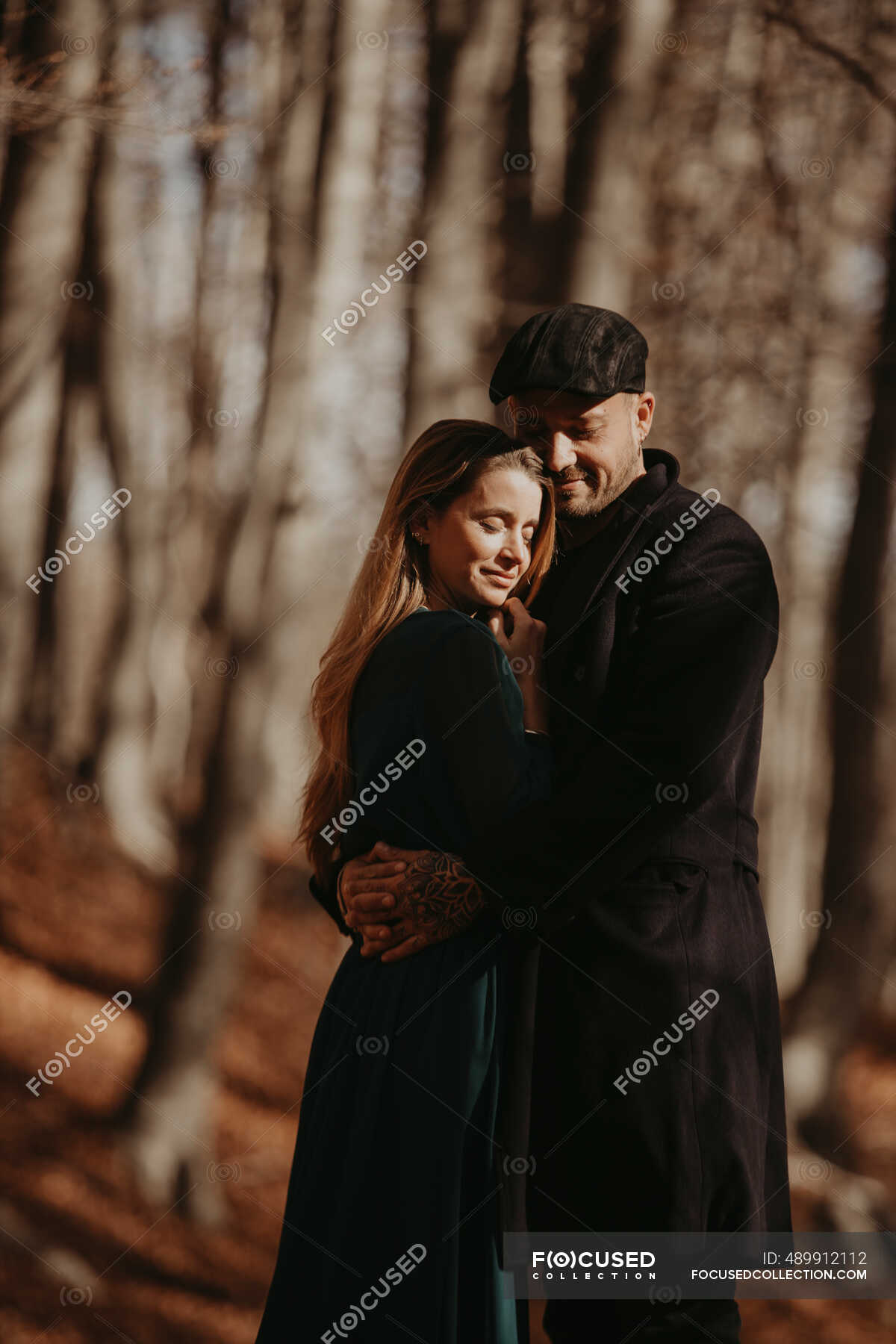 Boyfriend and girlfriend embracing in forest during sunny day ...