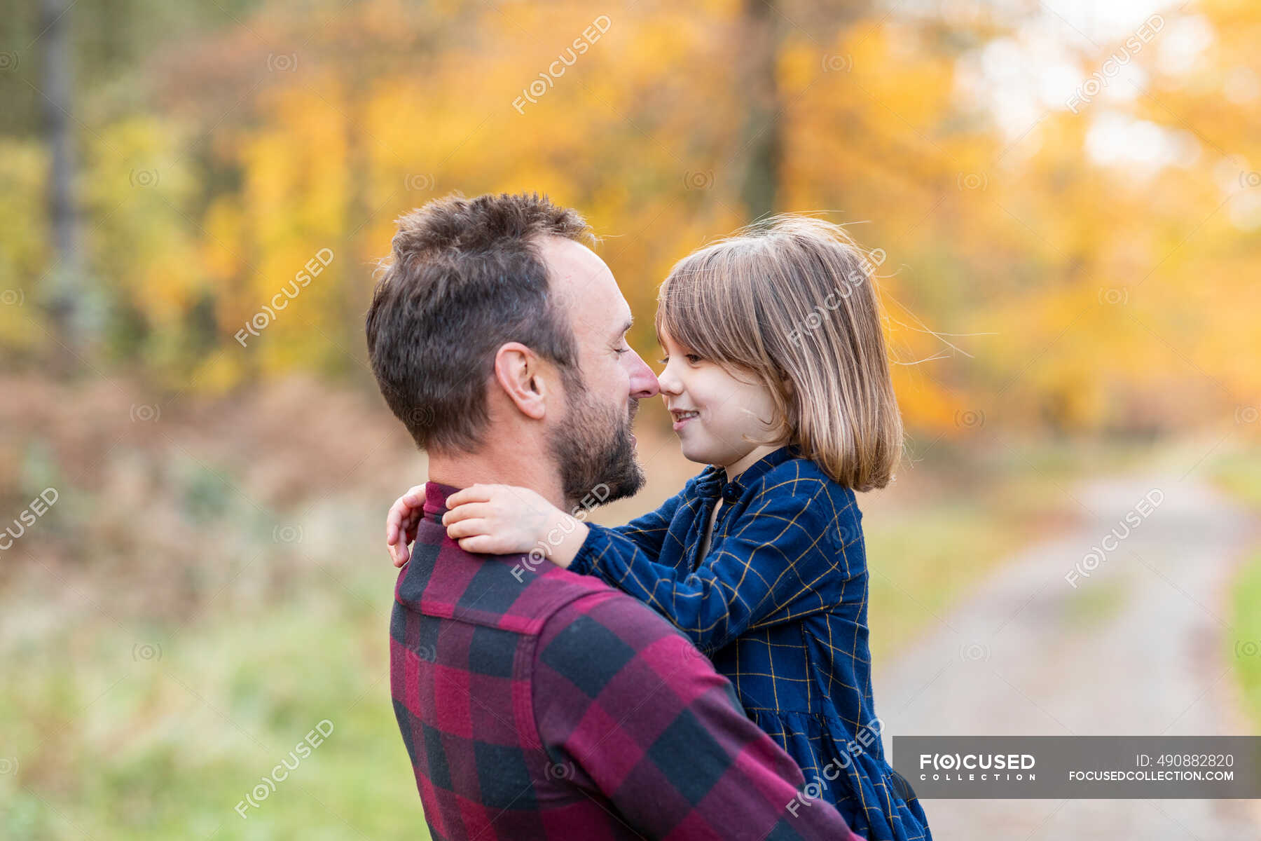 smiling-father-and-daughter-rubbing-nose-while-standing-in-forest