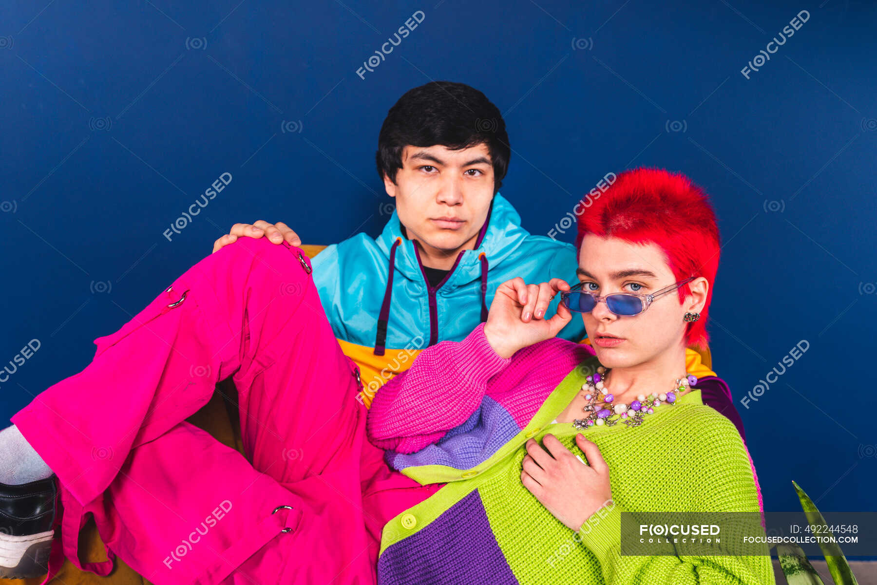 male-and-female-friends-sitting-in-front-of-blue-background-attitude