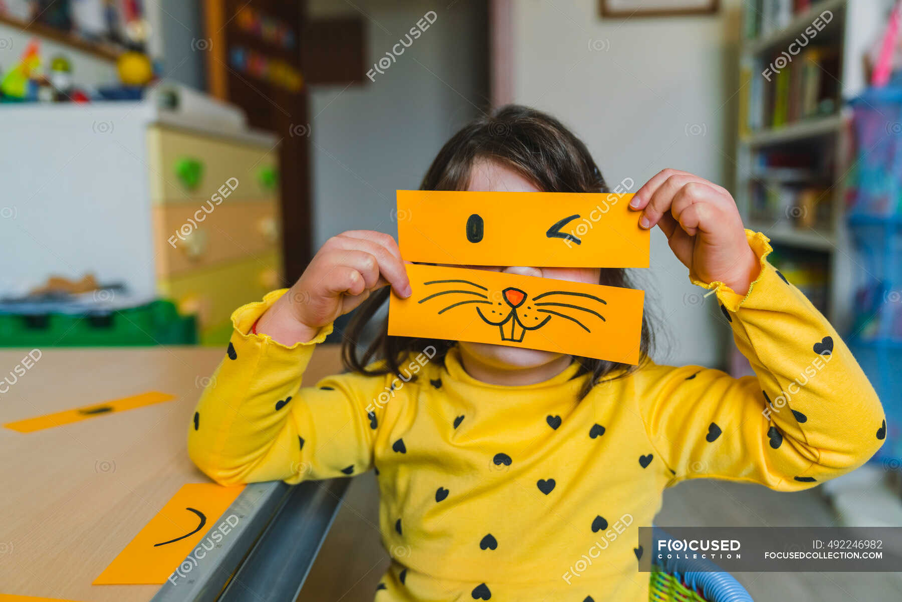 Girl holding animal and winking emoticon over face while playing at