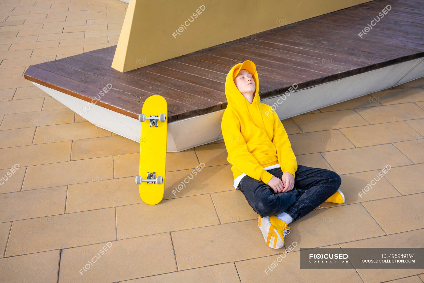 tired-boy-sitting-cross-legged-while-relaxing-on-footpath-teenager