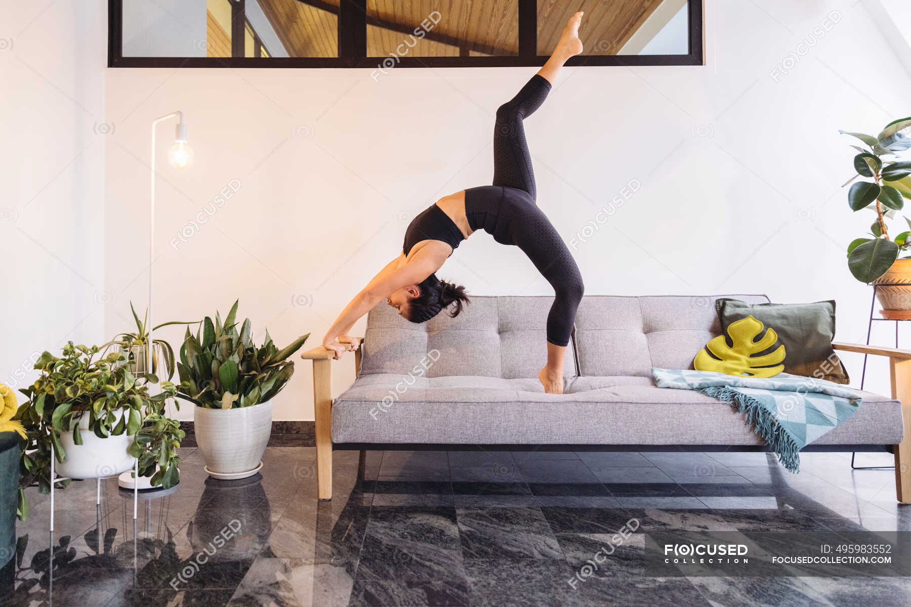 Woman practicing Yoga pose on sofa against wall in living room at home —  couch, 40s - Stock Photo | #495983552