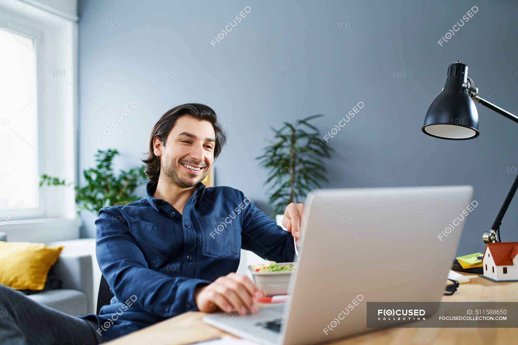 Smiling businessman using laptop at desk while sitting in office