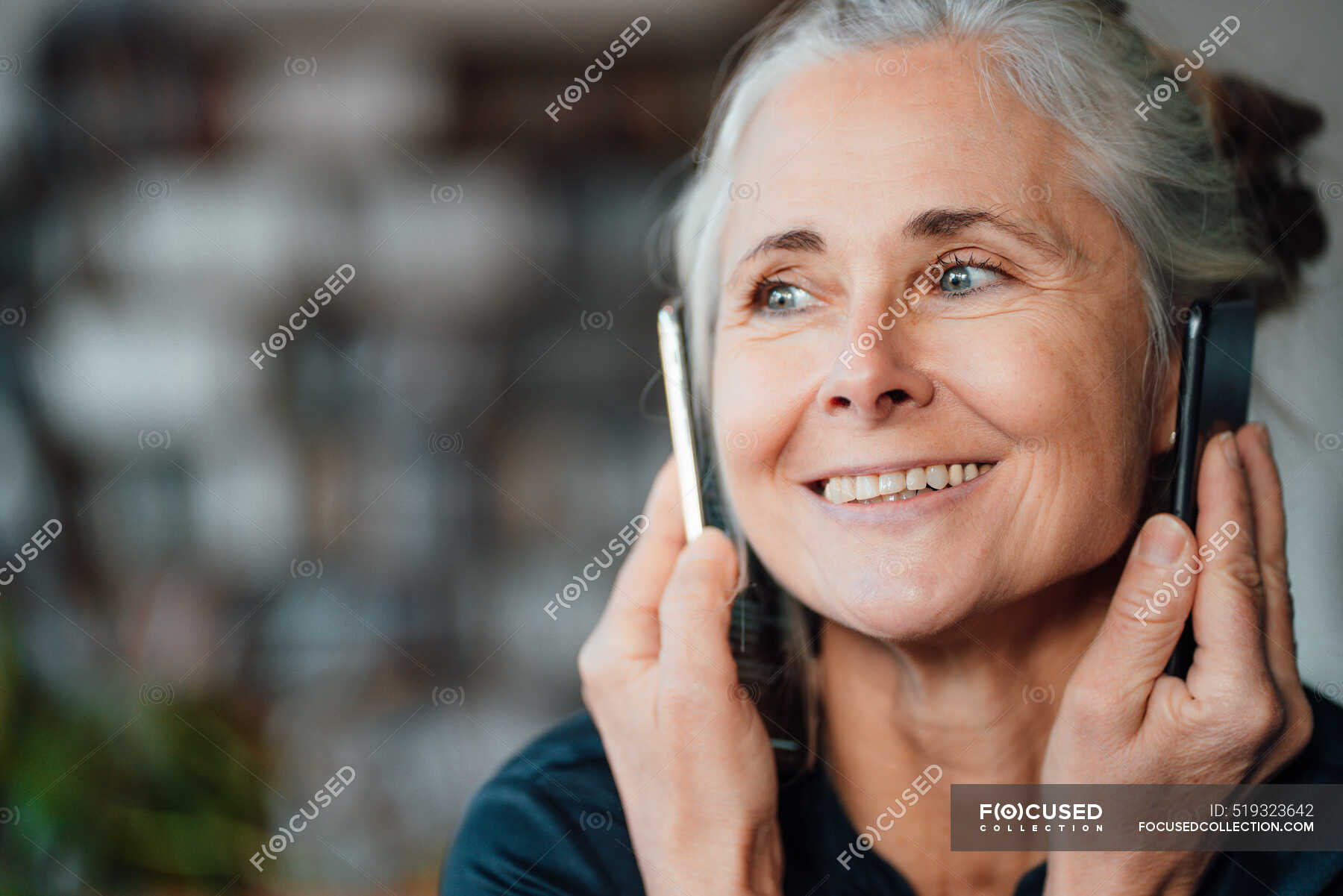 smiling-businesswoman-talking-on-mobile-phones-at-cafe-50-60-years