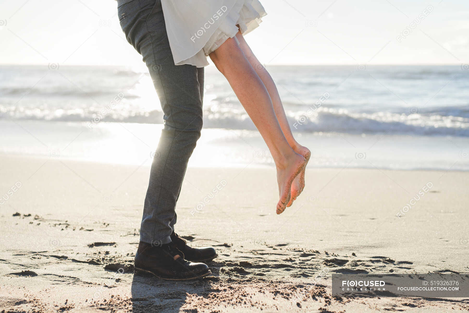 Groom picking up bride at beach during sunrise — couple, atmosphere ...