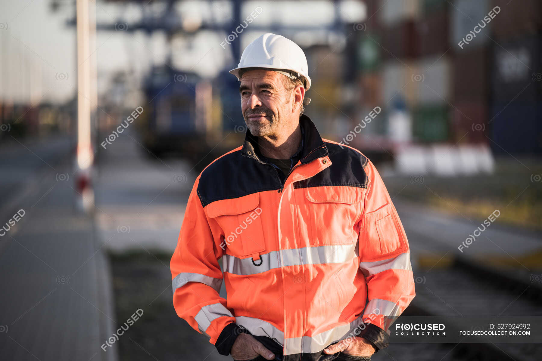 male-dock-worker-with-hands-in-pockets-standing-at-industry-looking