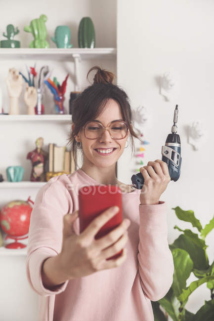 Mujer tomando selfie con destornillador eléctrico - foto de stock