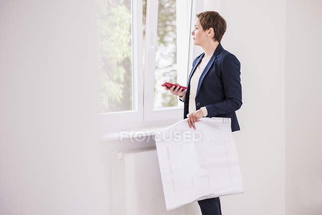 Woman standing with plan and cell phone — Stock Photo