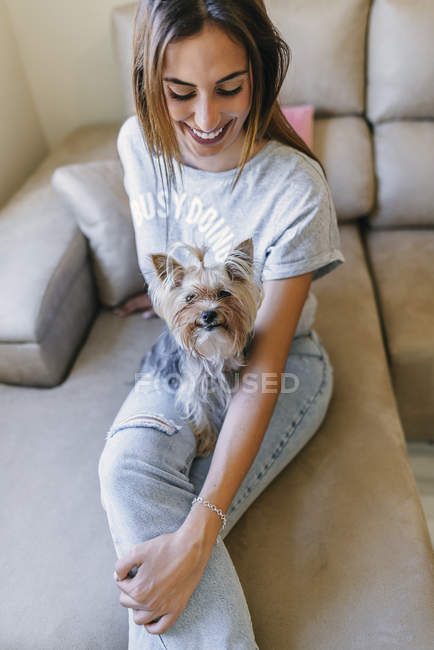 Woman sitting on couch with Yorkshire Terrier — Stock Photo