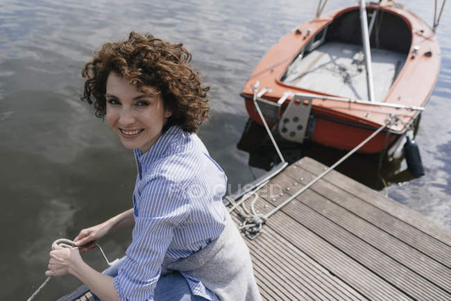 Woman standing on jetty with moored boat — Stock Photo