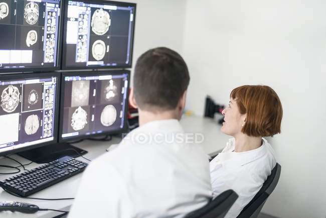Due medici discutono immagini a raggi X sugli schermi del computer — Foto stock
