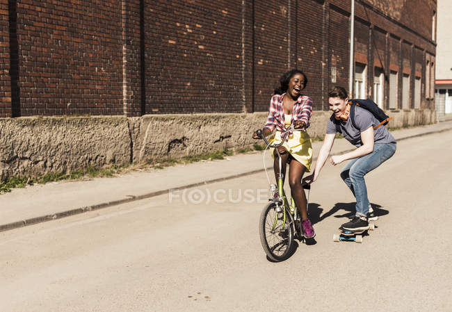 Woman on bicycle pulling man — Stock Photo