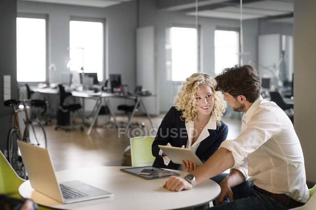 Бізнесмен і жінка обговорення проекту в офісі, використовуючи цифровий планшетний — стокове фото