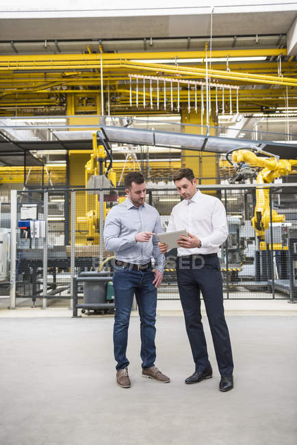 Men with tablet talking in factory — Stock Photo