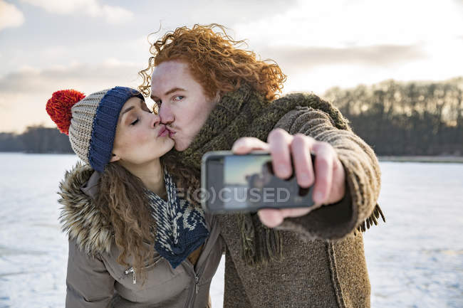 Paar küsst sich auf zugefrorenem See — Stockfoto