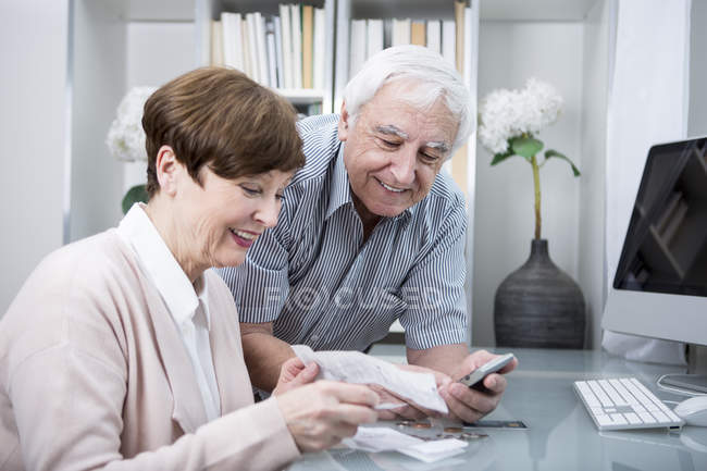 Couple aîné vérifiant les dépenses — Photo de stock