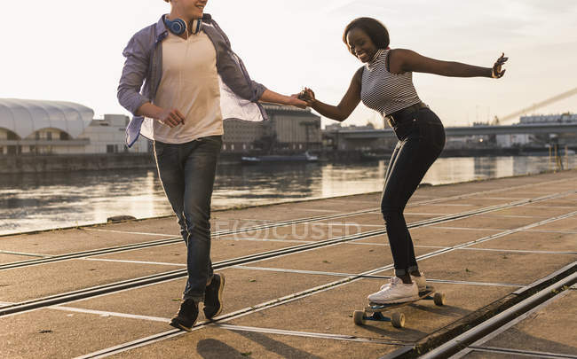 Casal de skate na margem do rio — Fotografia de Stock