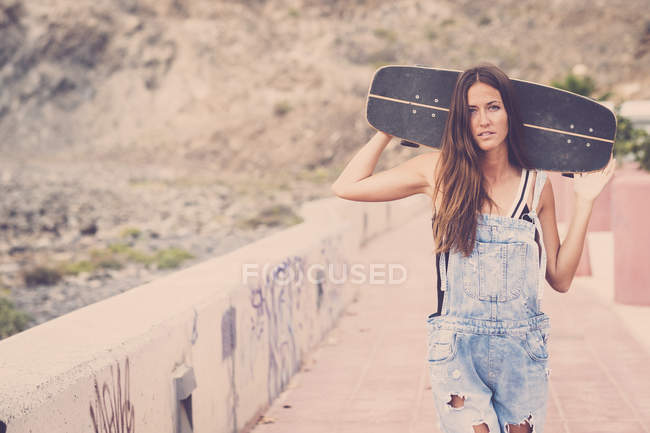 Frau hält Skateboard auf Schultern — Stockfoto