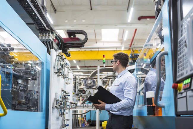 Mann mit Dokumenten steht in Fabrik — Stockfoto