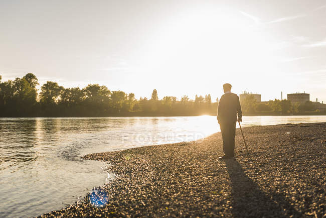 Senior steht am Flussufer — Stockfoto