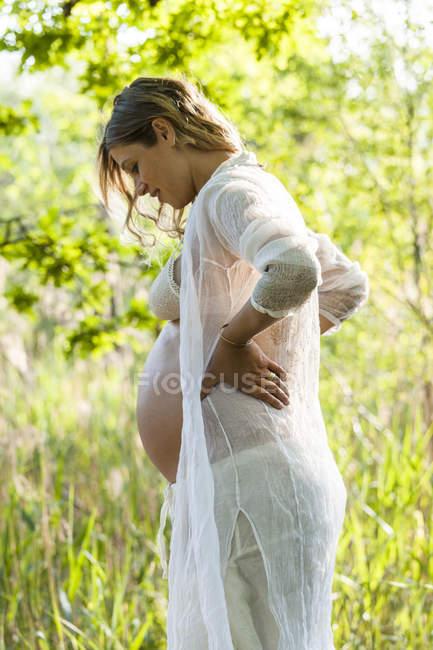 Sorridente donna incinta guardando giù — Foto stock