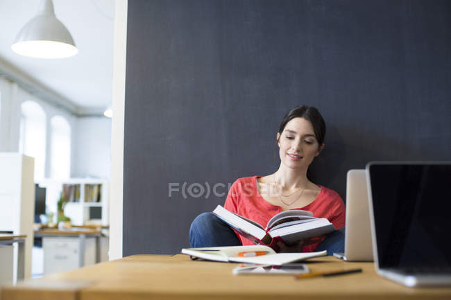 Женщина с книгой и ноутбуком — стоковое фото