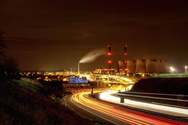 Vista a la central eléctrica de Ferrybridge por la noche con autopista en primer plano, West Yorkshire, Inglaterra, Reino Unido - foto de stock