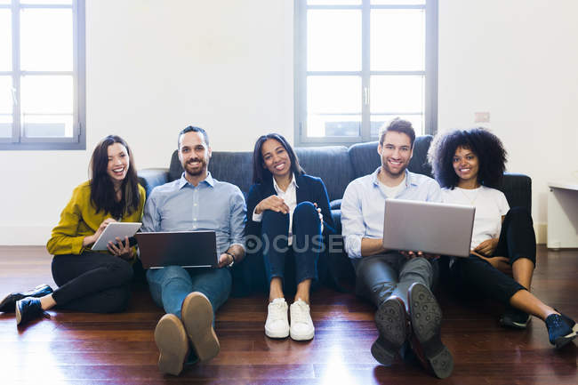 Коллеги сидят на диване с ноутбуками — стоковое фото