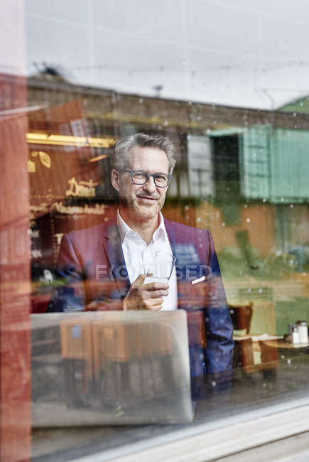 Geschäftsmann mit Laptop schaut aus dem Fenster — Stockfoto