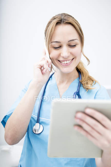 Arzt am Telefon schaut auf Tablet — Stockfoto