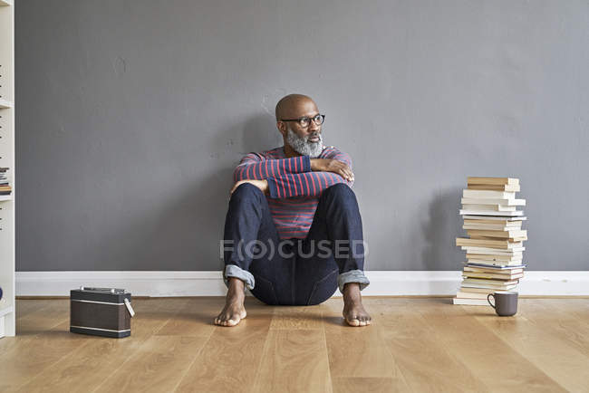 Мечтательный человек, сидящий на полу — стоковое фото
