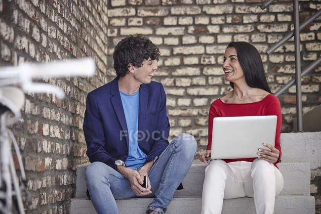 Colleagues sitting on stairs and using laptop — Stock Photo