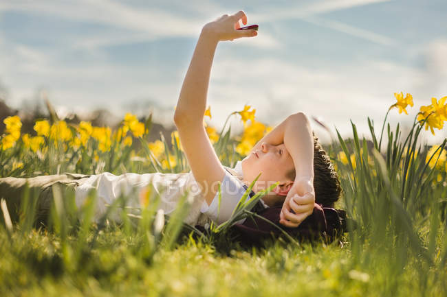 Rapaz deitado no campo de narcisos — Fotografia de Stock