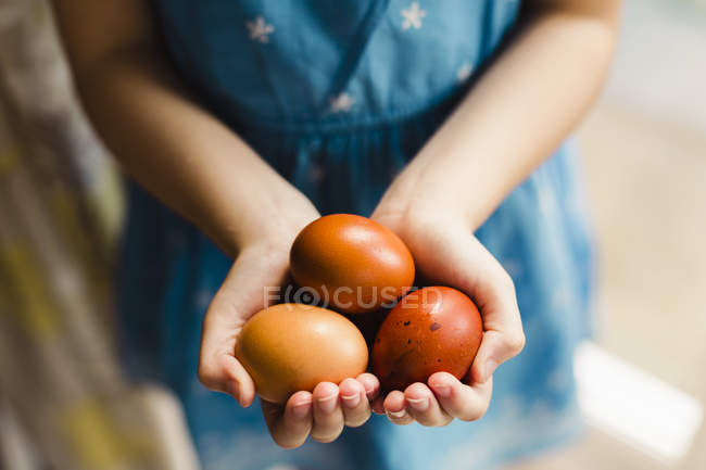 Mädchen hält drei braune Eier — Stockfoto