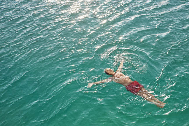Mann treibt im türkisfarbenen Wasser — Stockfoto
