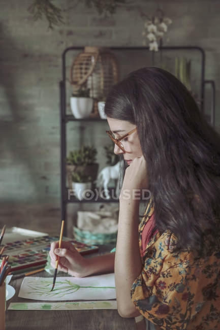 Woman painting plants with watercolors — Stock Photo